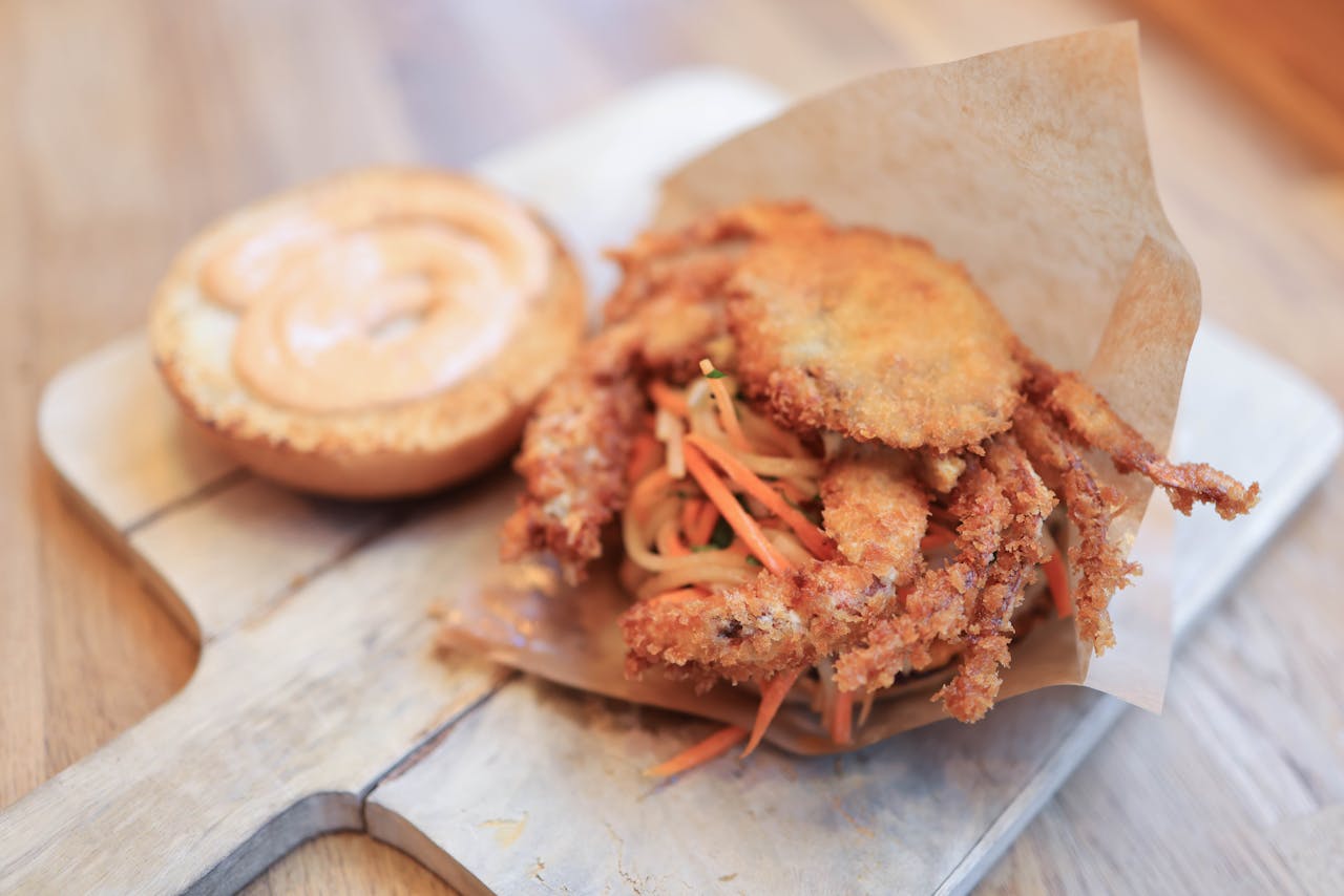 Close-up of a crispy soft shell crab sandwich with savory sauce. Perfect for seafood lovers.